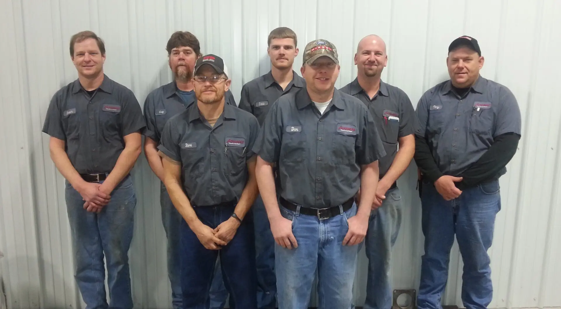 Seven men in work shirts smiling