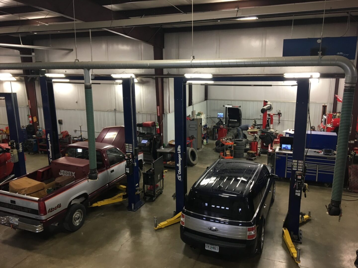 A garage with cars in it and people working on them.